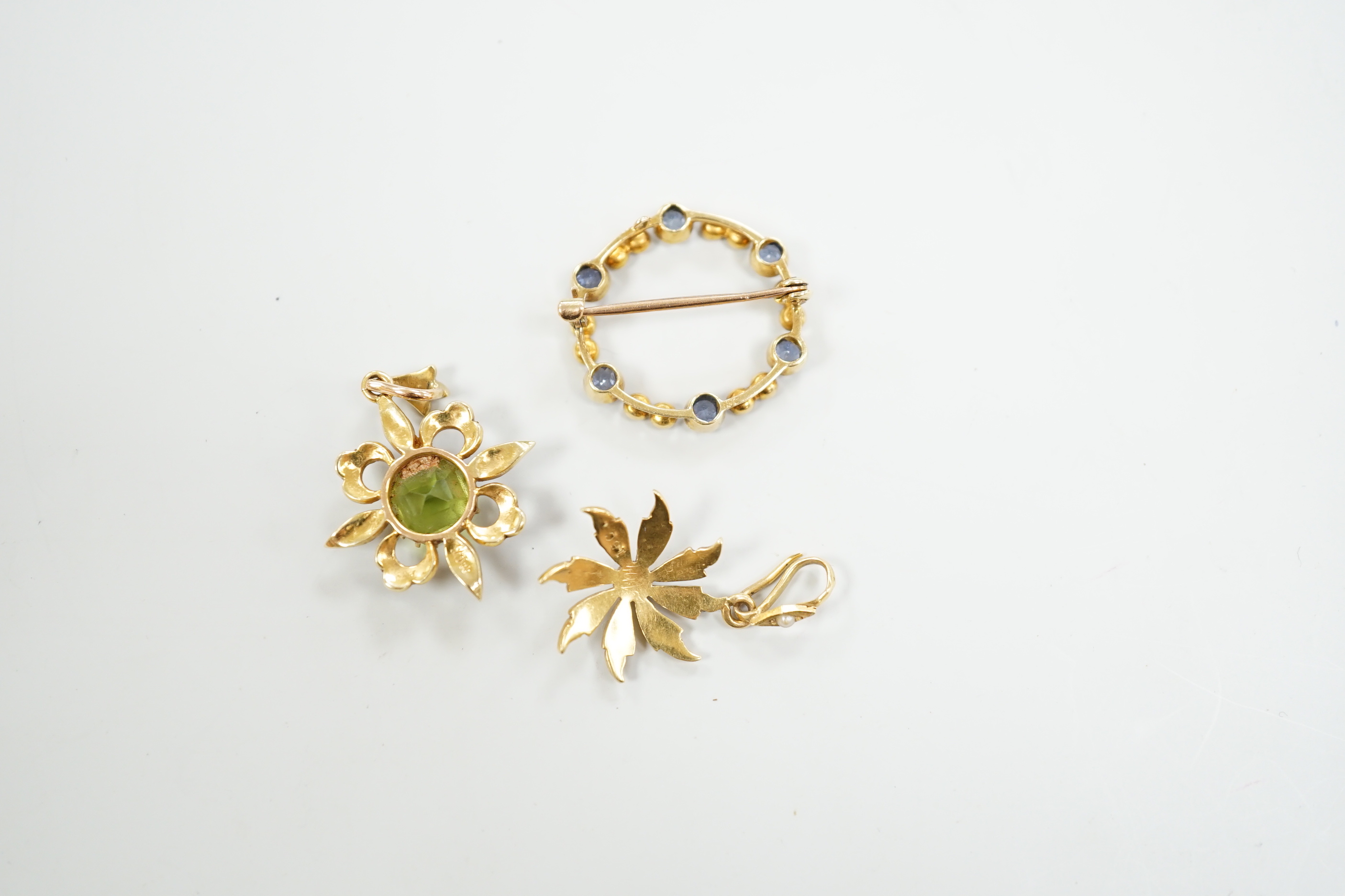 Two Edwardian 15ct and gem set pendants including peridot and seed pearl, 27mm and a similar 15ct and gem set open work circular brooch, gross weight 7 grams.
